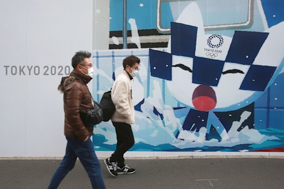 People walk by posters promoting the Olympic and Paralympic Games in Tokyo.