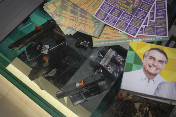 Campaign stickers for outgoing Brazilian President Jair Bolsonaro lie near guns for sale at a shooting club in Sao Paulo, Brazil, in October.