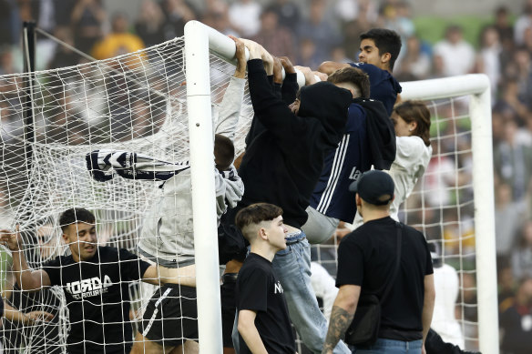 Fans swing on the goal after storming the pitch at AAMI Park on Saturday night.