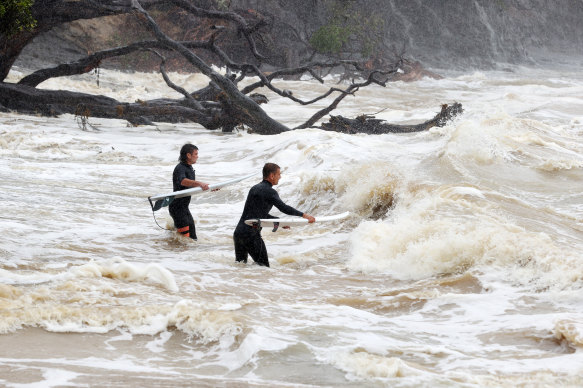 Surfers head out into large waves and rough seas from Cyclone Gabrielle at Goat Island Marine Reserve in Auckland.