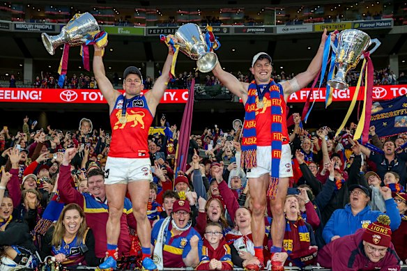 Dayne Zorko and Jarrod Berry hold the Lions’ three premiership cups.