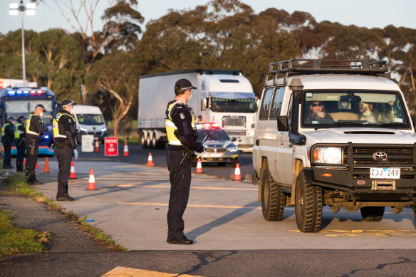 Victorian police wear masks and gloves as they stop drivers at a checkpoint on the Hume Freeway.