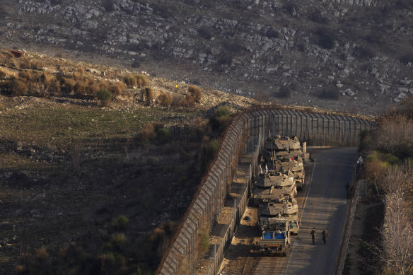Israeli soldiers walk near armoured vehicles parked along the so-called Alpha Line that separates the Israeli-annexed Golan Heights from Syria.