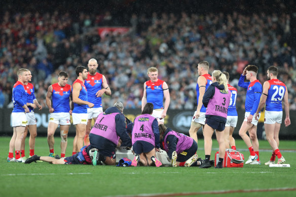 Melbourne players look on after midfielder Angus Brayshaw was knocked out by Collingwood defender Brayden Maynard.