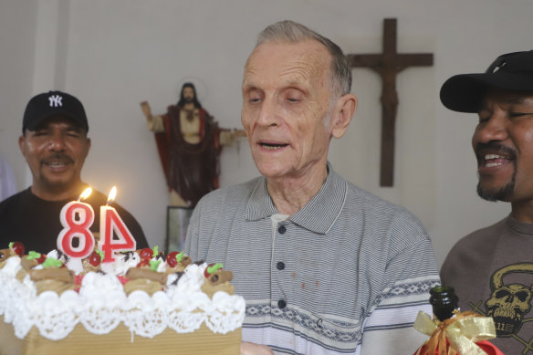 Daschbach, centre, is presented with a cake to celebrate his 84th birthday in Dili in January. 