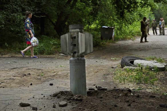 A woman carries her rubbish past an unexploded Russian Smerch rocket in the city of Kostyantynivka. 