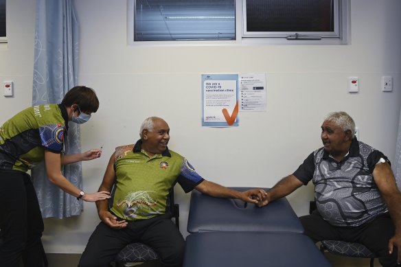 Dr Heather McKenzie administers a COVID-19 vaccination to Darryl Wright (centre) moments after Ivan Wellington (right) received his vaccination at Tharawal Corporation Medical Centre in western Sydney,