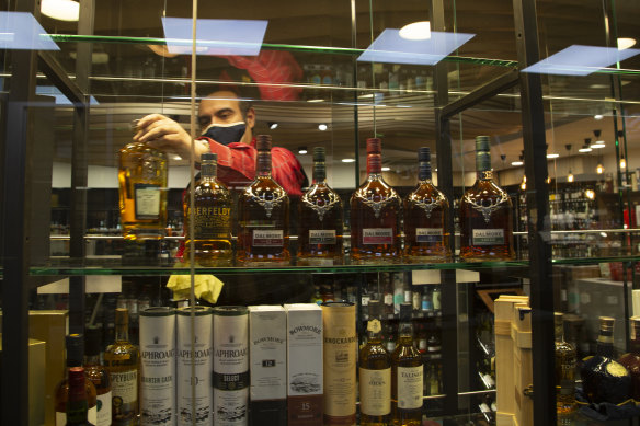 A man stocks a display shelf with bottles of alcohol at a Johannesburg liquor store.