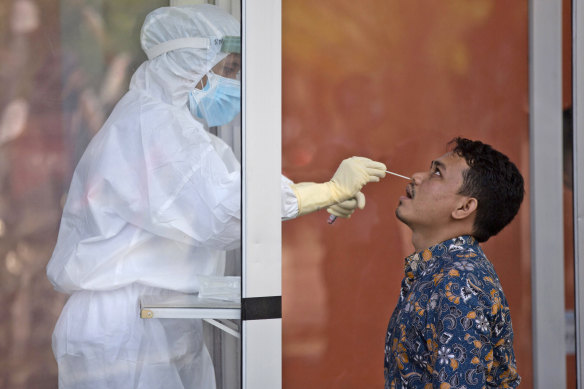 A man reacts as a medical worker collects his nasal swab samples during a test for coronavirus at North Sumatra University Hospital in Medan, North Sumatra, Indonesia.