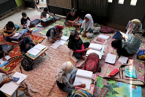 Teacher Inggit Andini, right, wearing face shield,  offered free extra lessons for students who lack access to the internet at her home in Tangerang, Indonesia.