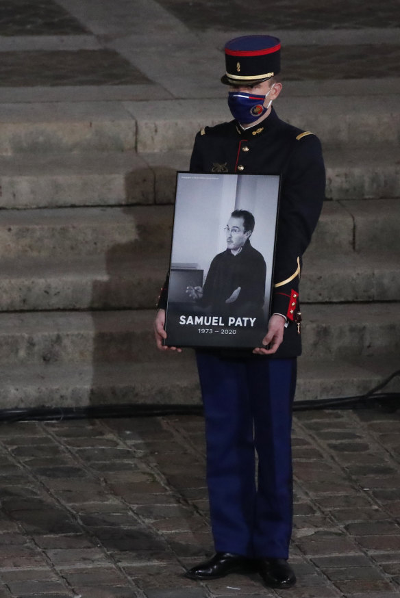 A Republican Guard holds a portrait of slain school teacher Samuel Paty during a memorial service in Paris.