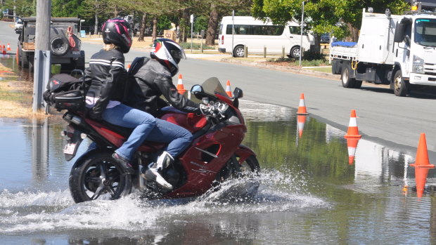 Motorbike riders travel through saltwater flooding in Scarborough, north of Brisbane.
