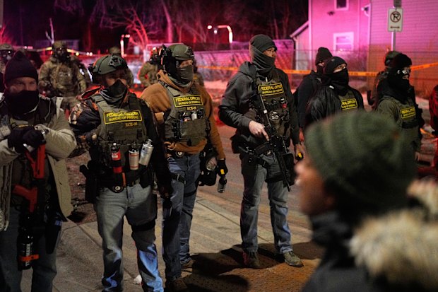 Federal law enforcement officers stand against protesters after a shooting in Minneapolis on Wednesday.