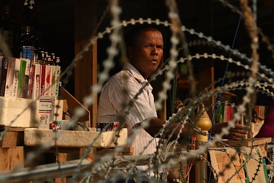 A man tends his market stall on a sandbar in the middle of the Moei River on the Thai- Myanmar border between Mae Sot and Myawaddy, Myanmar.