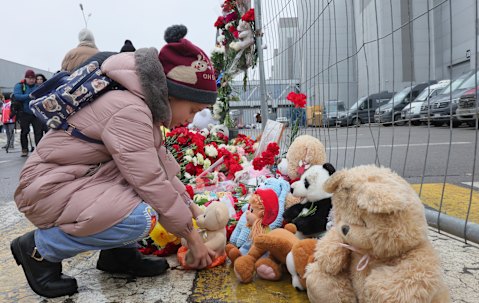 A child places a toy at the fence next to the Crocus City Hall, on the western edge of Moscow.