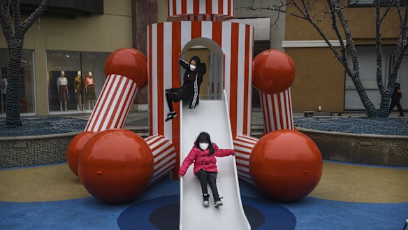 Chinese children wear protective masks as they play on a slide at a shopping mall in Beijing. 