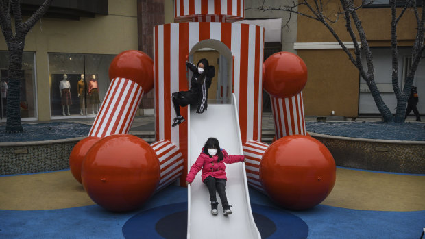 Chinese children wear protective masks as they play on a slide at a shopping mall in Beijing. 