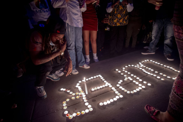 Maalik Mitchell, 20, mourns the death of his father Calvin Munerlyn, kneeling next to a display of candles that spell out Munerlyn's nickname "Duper" during a vigil in Flint.