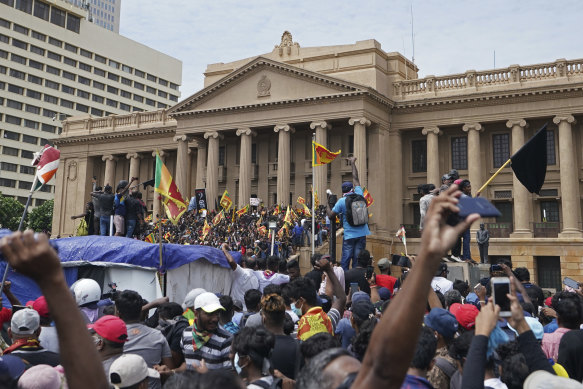 Protesters, many carrying Sri Lankan flags, gather outside the presidents office in Colombo on Saturday.