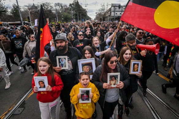 Relatives of Uncle Jack Charles carry pictures of family members on the march as it passed down Nicholson Street, Fitzroy.