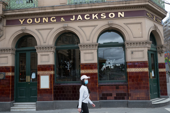 A pedestrian walking past the Young & Jackson pub in Melbourne.
