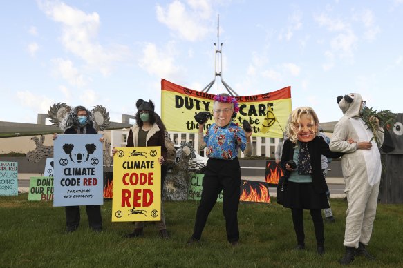 Extinction Rebellion protesters wearing Prime Minister Scott Morrison and Environment Minister Sussan Ley masks out the front of Parliament House.