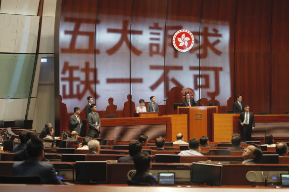 Carrie Lam, centre left, prepares to deliver her speech as protestors' slogans are projected on the wall of the Legislative Council.