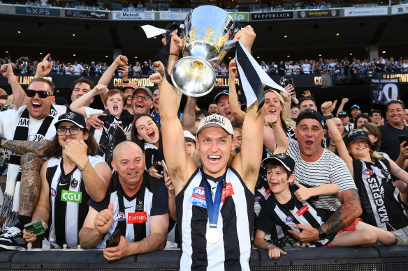 Collingwood captain Darcy Moore brandishes the cup to the Magpie army.