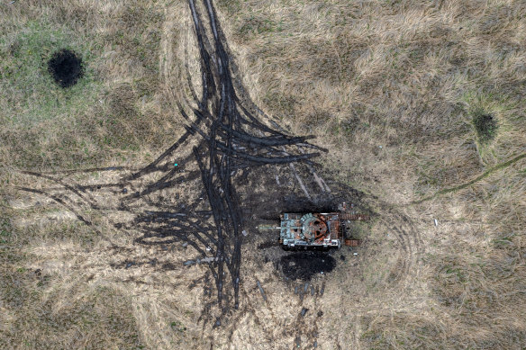 Artillery and mortar craters pierce the ground next to a destroyed Russian tank, on October 23, 2022 in Kam’yanka, Kharkiv.