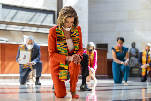 House Speaker Nancy Pelosi, centre, and other members of Congress, wear Kente cloth scarves while kneeling at the Capitol's Emancipation Hall, in Washington on Monday.