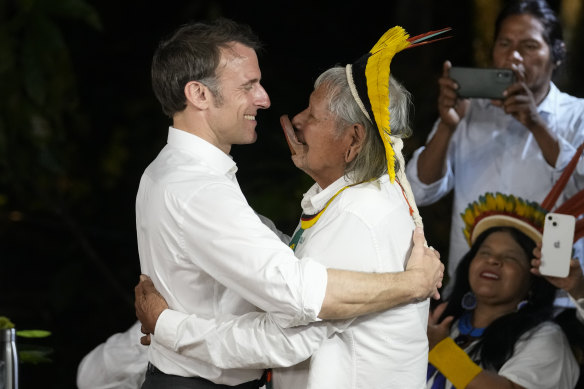French President Emmanuel Macron, left, embraces Chief Raoni Metuktire after presenting him with the French distinction, the Legion of Honour.