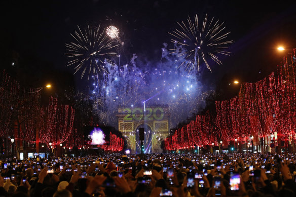 Revellers photograph fireworks over the Arc de Triomphe as they celebrate the New Year on the Champs-Elysees in Paris.