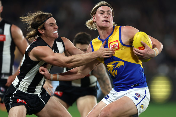 West Coast gun Harley Reid fends off a tackle from Collingwood’s Harvey Harrison.