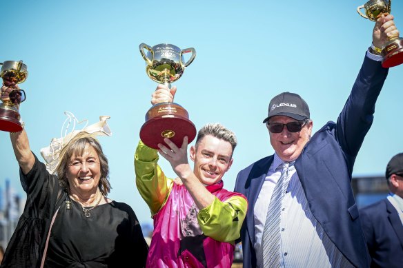 Jockey Robbie Dolan (centre) hoists the Melbourne Cup with trainers Sheila Laxon and John Symons.