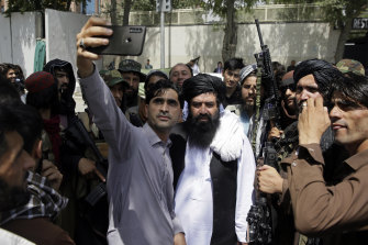 An Afghan takes a selfie with Taliban fighters on patrol in Kabul on Thursday.