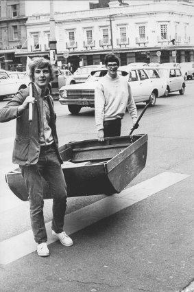 Photographer Fred Murray found Brian Griffiths (left) and Peter Williamson carrying their six-foot dinghy at Circular Quay. They'd rowed across harbour from Mosman, landed at Mrs. Macquarie's chair, and were carrying the boat up town. Then workmen at Circular Quay volunteered to mind the dinghy until the boys row home tonight. May 21, 1969.
