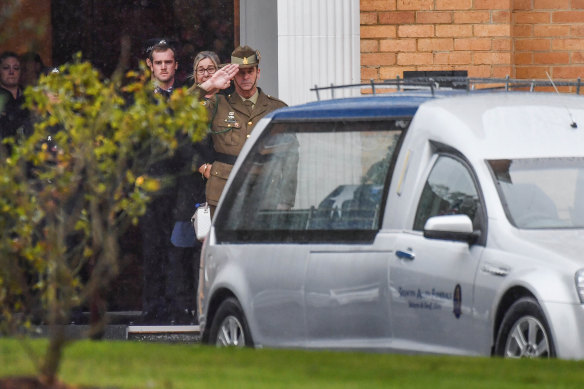 Todd Robinson salutes his long-term partner Glen Humphris following a private funeral service for the police constable at the Victoria Police Academy.