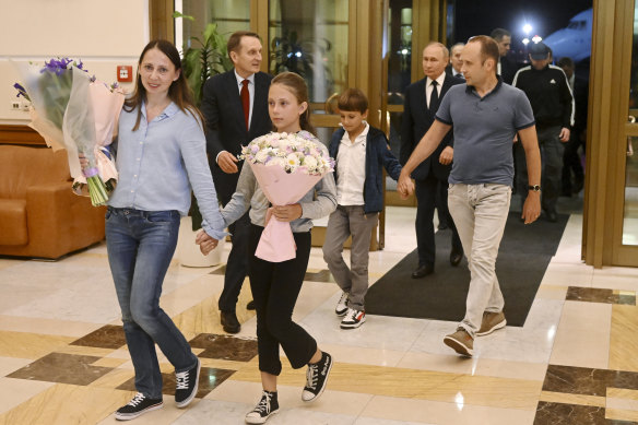 Vladimir Putin walks behind two convicted sleeper agents and their teenage children, who were deported to Russia from Slovenia as part of a landmark prisoner exchange.