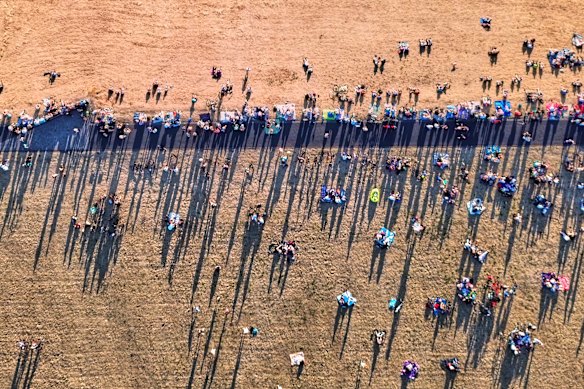 People cast long shadows while watching from the top of a mine dump in Gremany.