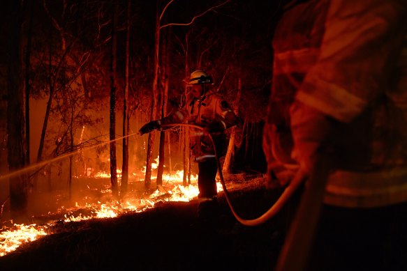 NSW RFS firefighters working to prevent a flare up from crossing the Kings Highway in between Nelligen and Batemans Bay in early January.