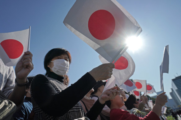 A Japanese well-wisher holds a national flag - called nisshoki or hinomaru - at the Imperial Palace before the royal motorcade of Emperor Naruhito and Empress Masako in Tokyo in 2019.