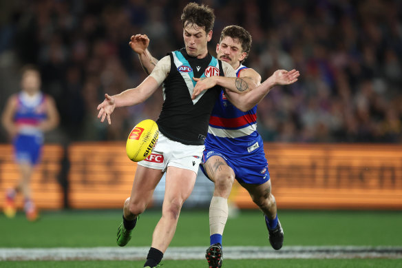 Zak Butters gets a kick away as  Tom Liberatore moves in to tackle.