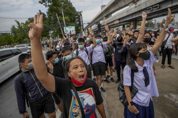 Pro-democracy protesters flash three-fingered salutes during a demonstration in Bangkok.