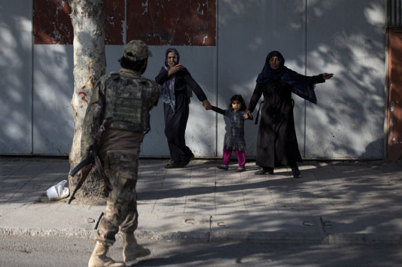A Taliban soldier sends people away after an explosion at the entrance of a military hospital in Kabul.