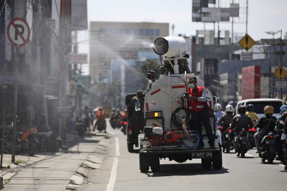 A truck sprays disinfectant to help reduce the spread of the coronavirus on a street in Jakarta, Indonesia, on Tuesday.
