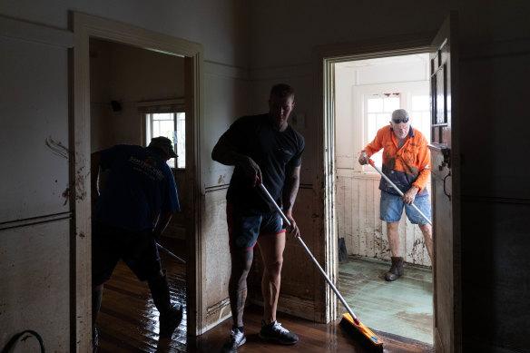 Family and friends sweep water out of the Temporini home on Monday.