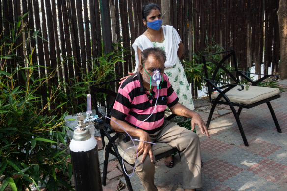 A daughter pats the back of her father as he struggles to breathe with the aid of supplemental oxygen in Bengaluru, India.