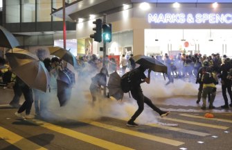 A protester kicks a police tear gas shell away during clashed outside a shopping centre in Hong Kong on Sunday.