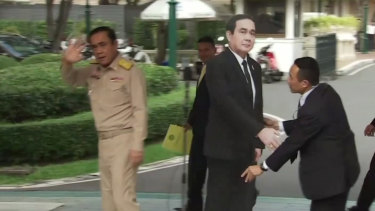 The Thai PM waves and walks off after the cardboard cut-out of himself is placed beside the microphone.