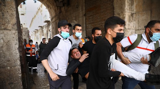 Palestinians evacuate a wounded protester during clashes with Israeli security forces at the Lions Gate in Jerusalem’s Old City, Monday, May 10, 2021.